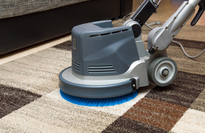 A rug is being cleaned by a professional rug cleaning machine.