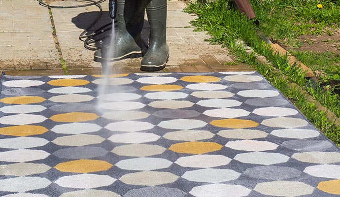 Person cleaning outdoor rug