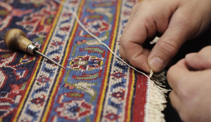 Person repairing rug fringe using equipment