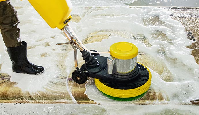A person cleaning a rug using equipment